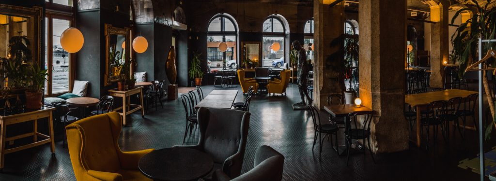 Stylish cafe interior with high ceilings, arched windows, and comfortable seating.